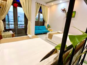 een hotelkamer met 2 bedden en een bank bij Bui Family Homestay in Hội An