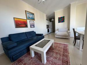 a living room with a blue couch and a table at Sunset Apartment in Vlorë