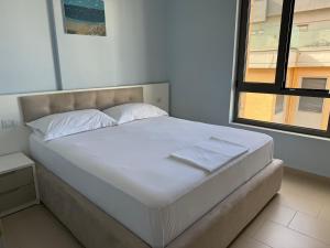 a bed with white sheets and a window in a room at Sunset Apartment in Vlorë +13 photos