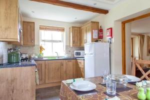 a kitchen with wooden cabinets and a white refrigerator at Plas Drygarn Ty Gwyrdd Crymych in Crymmych Arms