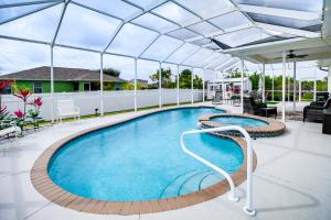 a large swimming pool with a roof at Lovely Lehigh Acres Home with Lanai, Pool and Spa! in Lehigh Acres