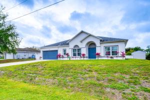 een wit huis met een blauwe garage bij Lovely Lehigh Acres Home with Lanai, Pool and Spa! in Lehigh Acres