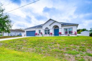 a white house with a blue garage at Lovely Lehigh Acres Home with Lanai, Pool and Spa! in Lehigh Acres
