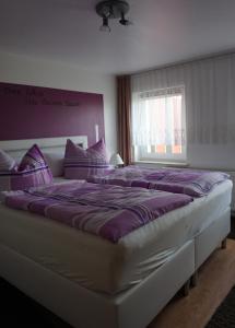 a bedroom with a large bed with purple pillows at Ferienhaus Müritz - Brockmann in Warenshof