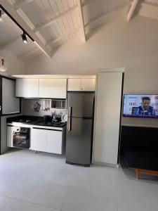 a kitchen with a stainless steel refrigerator and a tv at Praia do Forte / Studio in Mata de Sao Joao