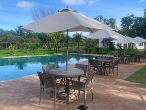 a table and chairs with an umbrella next to a pool at Praia do Forte / Studio in Mata de Sao Joao
