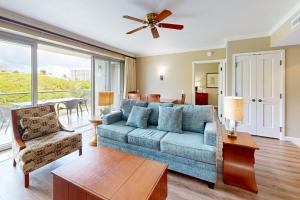 a living room with a blue couch and a ceiling fan at Honua Kai - Konea 446 in Lahaina