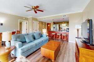 a living room with a blue couch and a kitchen at Honua Kai - Konea 446 in Lahaina