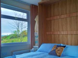 a bedroom with a bed with a large window at Sea Moss Cabin in Tywyn