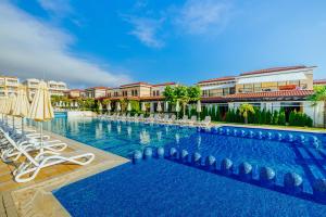 ein großer Pool mit Stühlen und Sonnenschirmen in der Unterkunft Green Life Sozopol Antares in Sozopol