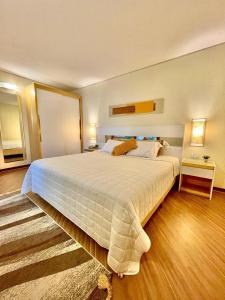 um quarto grande com uma cama grande e lençóis brancos em 102 · Apto no batel c/ Ar condicionado em Curitiba