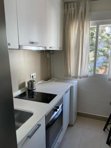 a white kitchen with a sink and a stove at Exyca Tetuán in Madrid