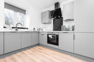 een witte keuken met witte apparatuur en een houten vloer bij Stylish 2 Bedroom Apartment - Gated Parking & Balcony - Top Rated - 8MC in Birmingham