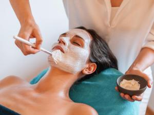a woman getting a face mask at a spa at Gesundhotel Bad Reuthe in Vorderreuthe