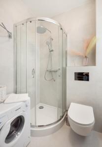 a bathroom with a shower and a toilet and a washing machine at Nowolipki Chic Studio in Warsaw