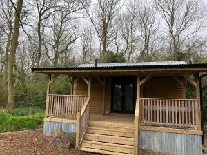 a large wooden cabin with a porch in the woods at Deer View Cabin - Woodland, beaches and Hot tub in Hull