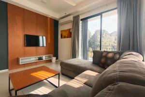 a living room with a couch and a tv at Sunway Onsen Suites - Theme Park Tambun Ipoh by Ryokan Management in Tambun