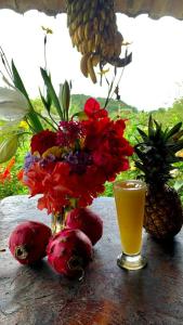 a table with a vase of flowers and a glass of juice at Finca Neblina del Bosque in Estelí