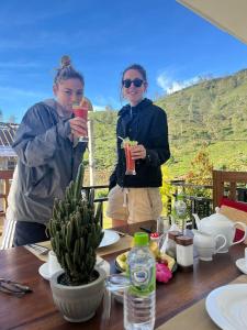 two women are standing at a table with drinks at Queensland Hotel in Nuwara Eliya