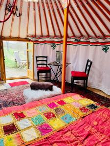 Bett in einem Zelt mit 2 Stühlen und einem Tisch in der Unterkunft Les Yourtes Ô fil 2 l'eau in Saint-Jean-Saint-Maurice-sur-Loire