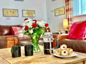 a coffee table with a vase of flowers and cookies at Watch Cottage in Brook