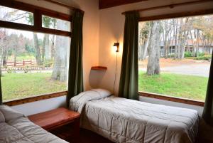 a bedroom with two beds and a large window at Cabañas la Villa del Montañes in Villa La Angostura