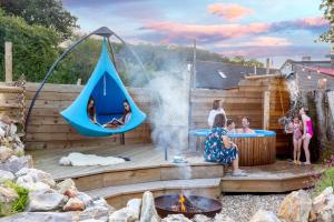 a group of people in a backyard with a hammock and a fire pit at Smallicombe Farm in Colyton