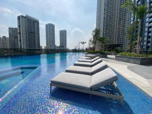 a row of lounge chairs sitting in a swimming pool at Lumiere Riverside - Raymond Holm - Luxurious 5-star apartment in Ho Chi Minh City