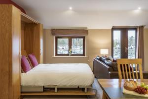 a bedroom with a bed and a table and a couch at Lakeland Apartment At Windermere Marina Village in Bowness-on-Windermere
