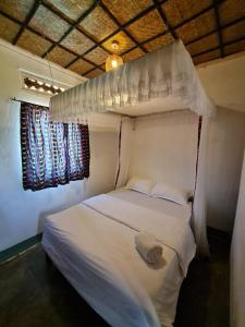 a bedroom with a white bed and two windows at Rwekishokye Country Club in Mbarara