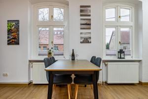 a dining room with a table and chairs and windows at Storchenzimmer 2 in Buchholz
