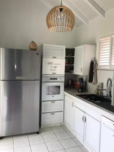 uma cozinha com armários brancos e um frigorífico de aço inoxidável em Superbe Villa de vacances aux Trois ilets em Les Trois-Îlets