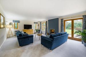 a living room with two blue couches and a tv at Treetops in Wimborne Minster