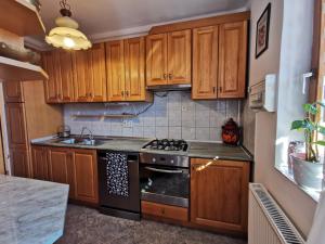 a kitchen with wooden cabinets and a stove top oven at Júlia Apartman in Balatonalmádi