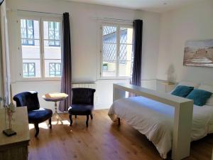 a bedroom with a bed and two chairs and two windows at Appart Rouen Centre in Rouen