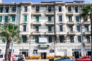 Ithaka Hostel في الإسكندرية: مبنى ابيض كبير فيه سيارات تقف امامه