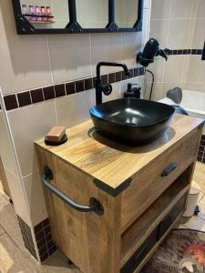 - un lavabo noir sur une coiffeuse en bois dans la salle de bains dans l'établissement Chambre d'hôtes "Sur la route des Terrils", à Vendin-le-Vieil