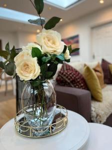 a vase filled with white roses sitting on a table at Sunny London Garden Apartment in London
