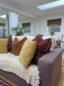 a couch with pillows on it in a living room at Sunny London Garden Apartment in London