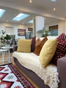 um sofá com almofadas num quarto em Sunny London Garden Apartment em Londres
