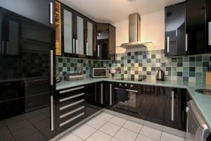 a kitchen with black and green tiles on the counters at Stylish Merchant City Apartment in Glasgow