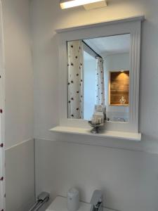 - un miroir au-dessus d'un lavabo dans la salle de bains dans l'établissement Gasthaus Krone Holzschlag, à Bonndorf im Schwarzwald