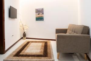 a living room with a chair and a television at 5 bdr house near Praça Center, AC & Wifi - LCGR in Praia