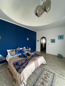a bedroom with a large bed with a blue wall at Dar El Kahina Djerba in Mezraya
