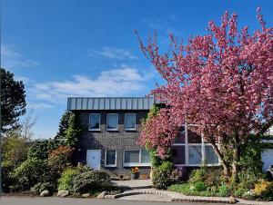 una casa con un árbol floreciente delante de ella en Die Villa Mettmann en Mettmann