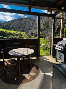 uma mesa e cadeiras sentadas num alpendre com um grelhador em Cabane em Olivese