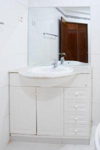 La salle de bains blanche est pourvue d'un lavabo et d'un miroir. dans l'établissement 5 bdr house near Praça Center, AC & Wifi - LCGR, à Praia
