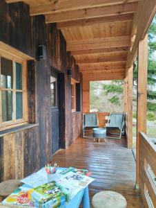 een veranda van een houten hut met een tafel en stoelen bij Agroturystyka 3 chaty red black I nanna in Młynary