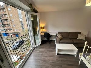 Renovu Exclusive Rooms London في لندن: غرفة معيشة مع أريكة وشرفة