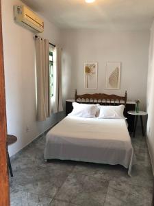 a bedroom with a bed with white sheets and a window at Tamboleiros Hotel & Hostel in Salvador